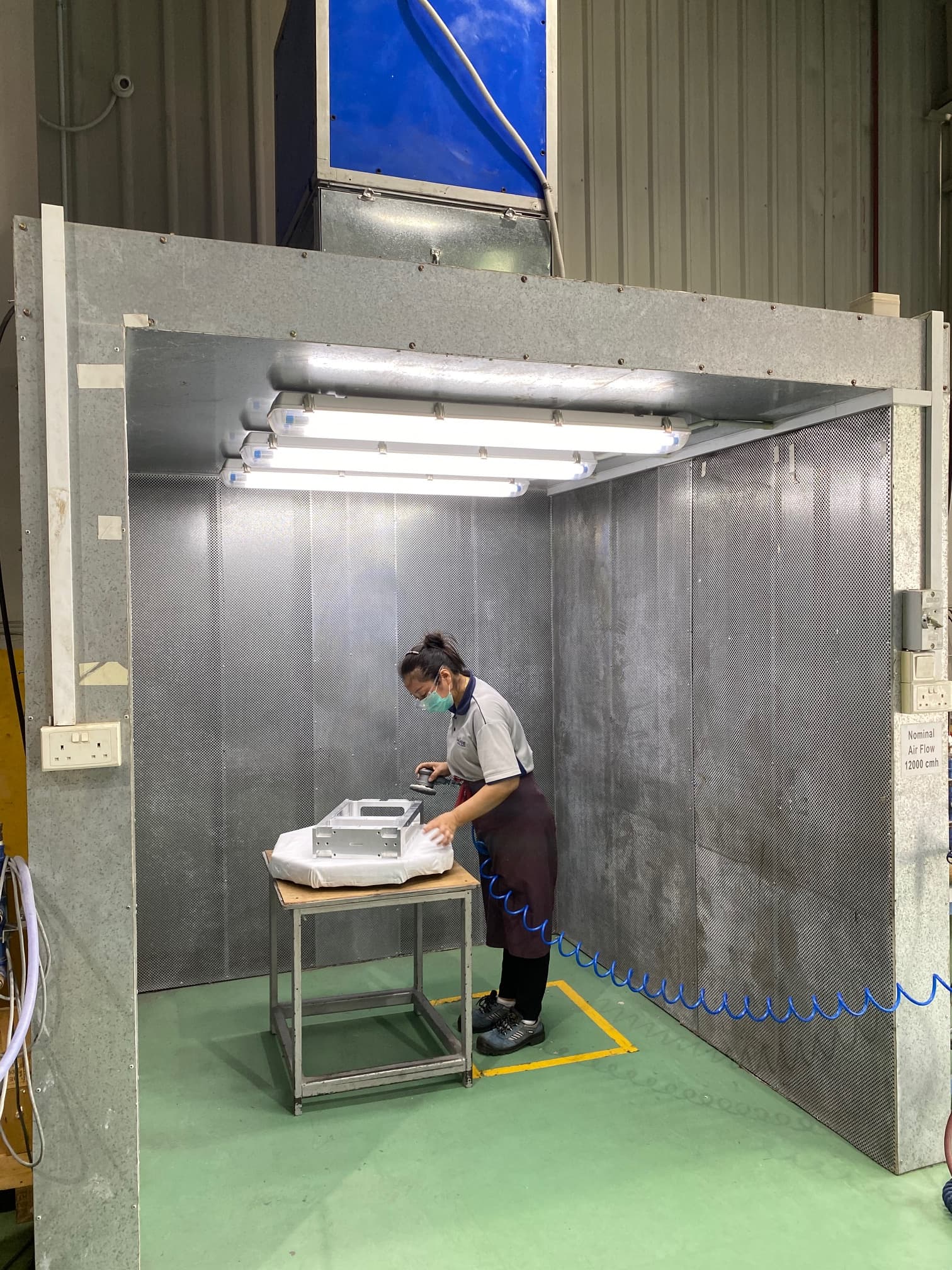 A staff performing deburring in an exhaust hood