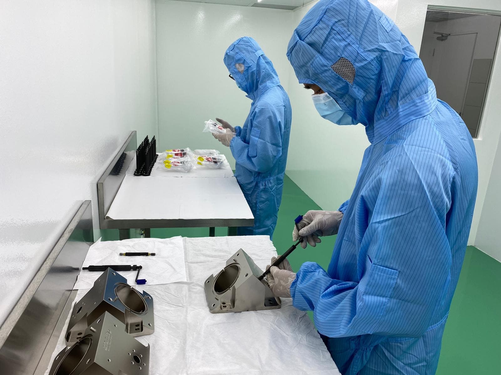 Two staff wearing PPE in a cleanroom performing assembly of a product