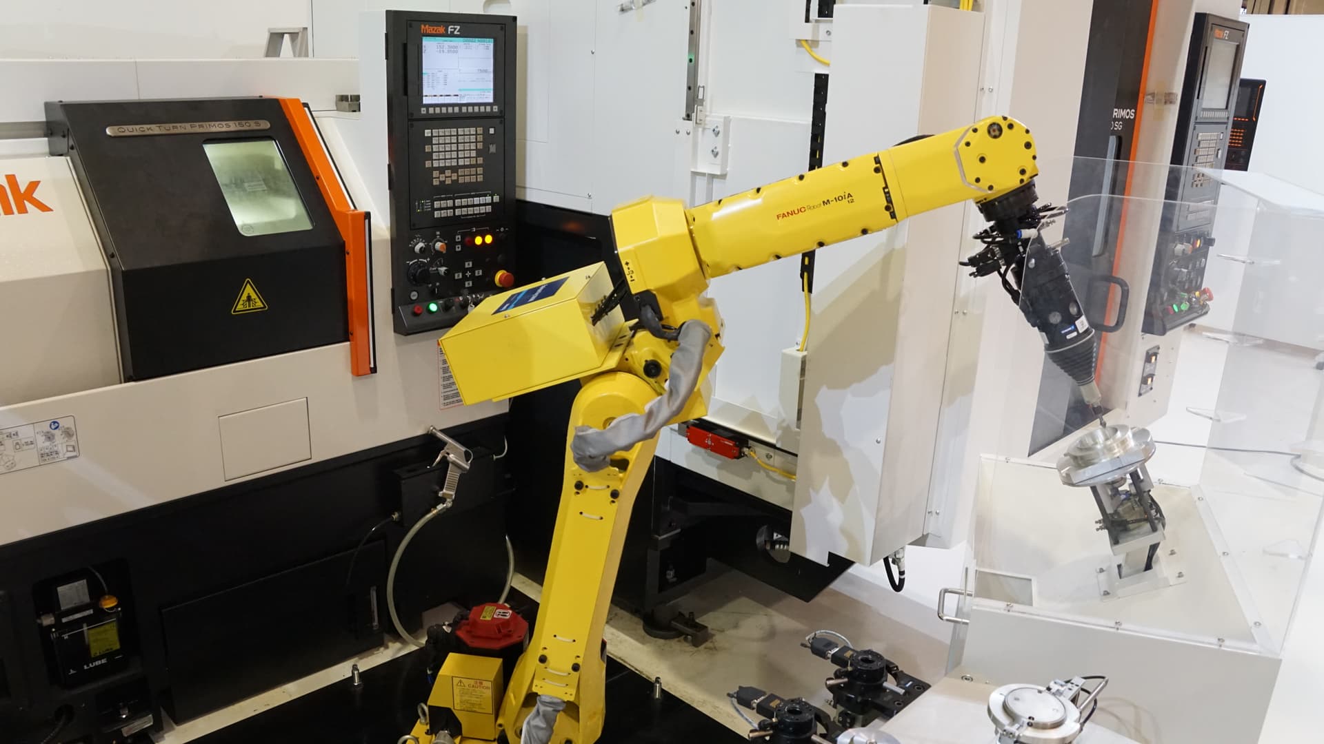 Robotic arm loading CNC machine, showcasing volume production